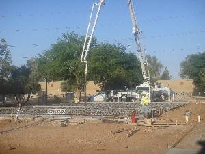 Workers supervise concrete truck pumping basketball court