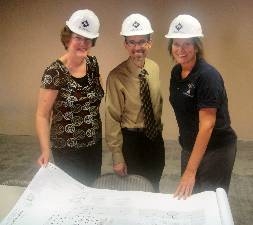 Three charter school board members with construction plans and hard hats