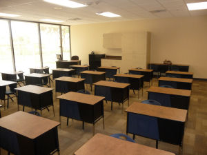 Elementary charter school classroom seen from the front. Sunny window overlooks the teacher desk in the back of the class.