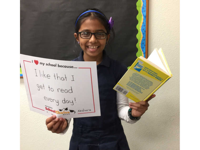 smiling middle school girl holds book and sign saying "I like that I get to read every day."