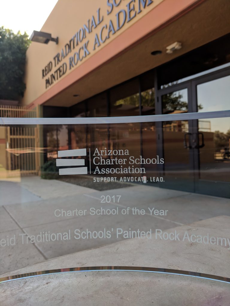 clear glass trophy for charter school of year in front of school entrance for painted rock academy