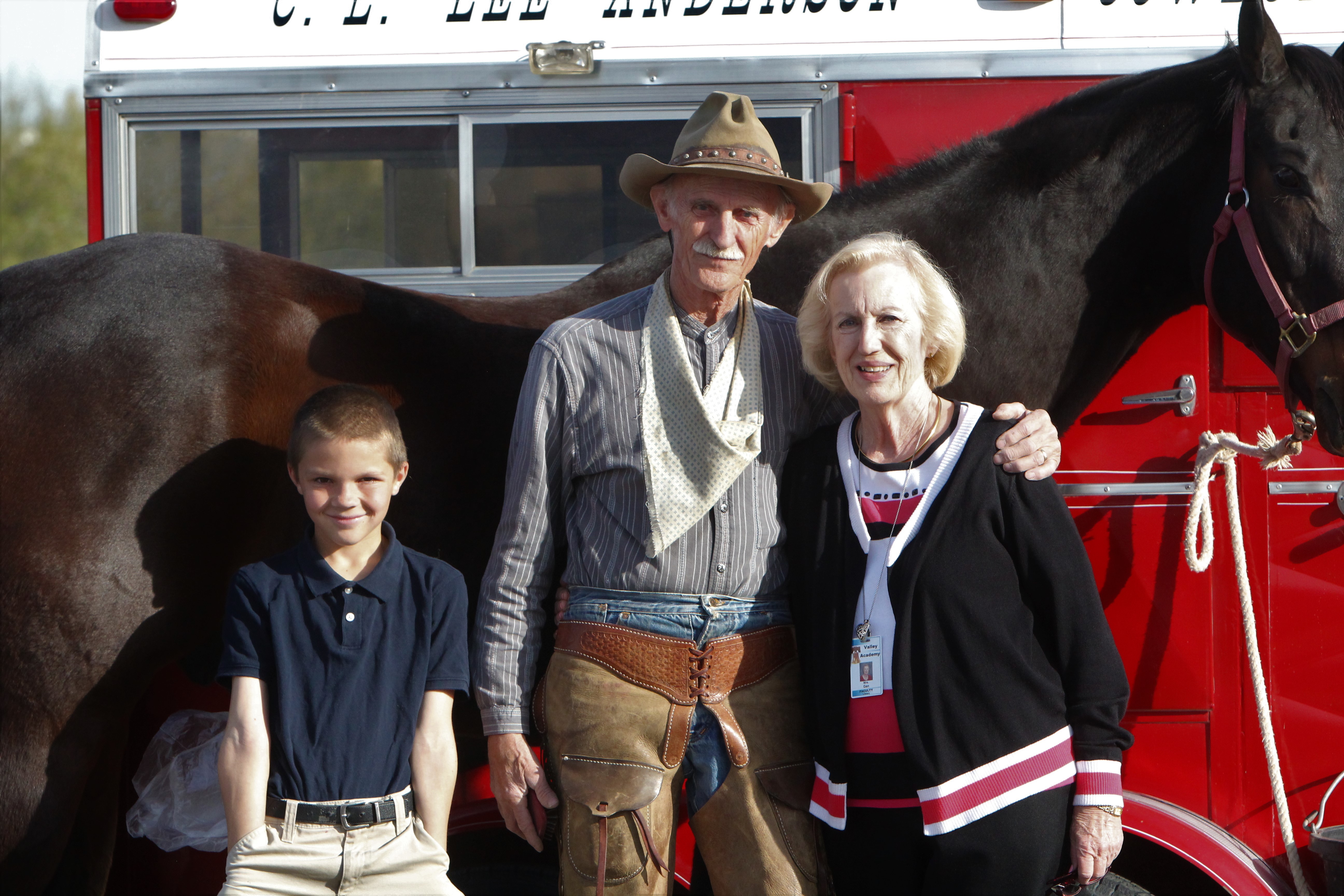 boy, cowboy, and librarian post in front of his horse and trailer