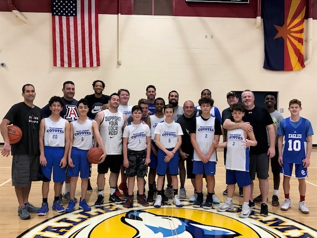 Junior High boys basketball team poses with their dads at center court