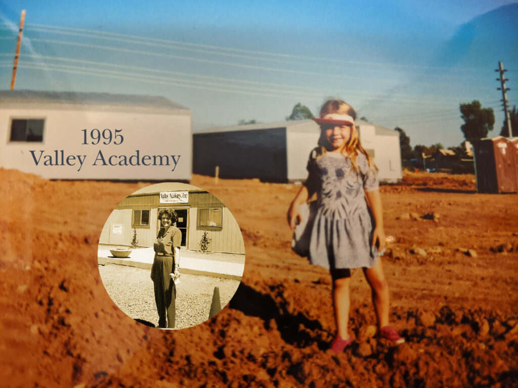 Young girl stands in dirt by portable school buildings labeled 1995 Valley Academy. Circle insert of her mother in front of School Office building.